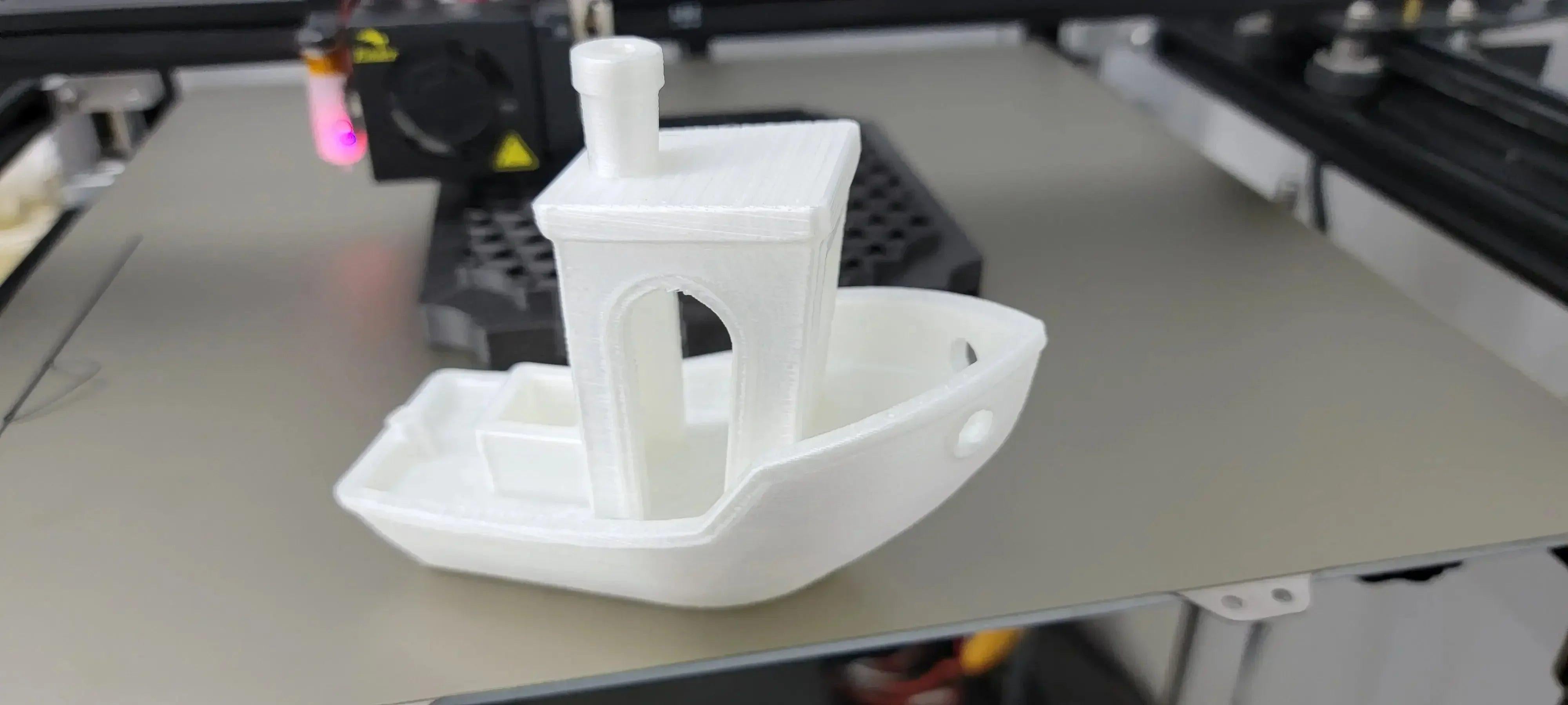 White nylon 3D printed boat model on a 3D printer bed, CoexNylex filament sample