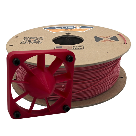 Spool of scarlet PETG 3D printer filament with a red 3D printed part in front