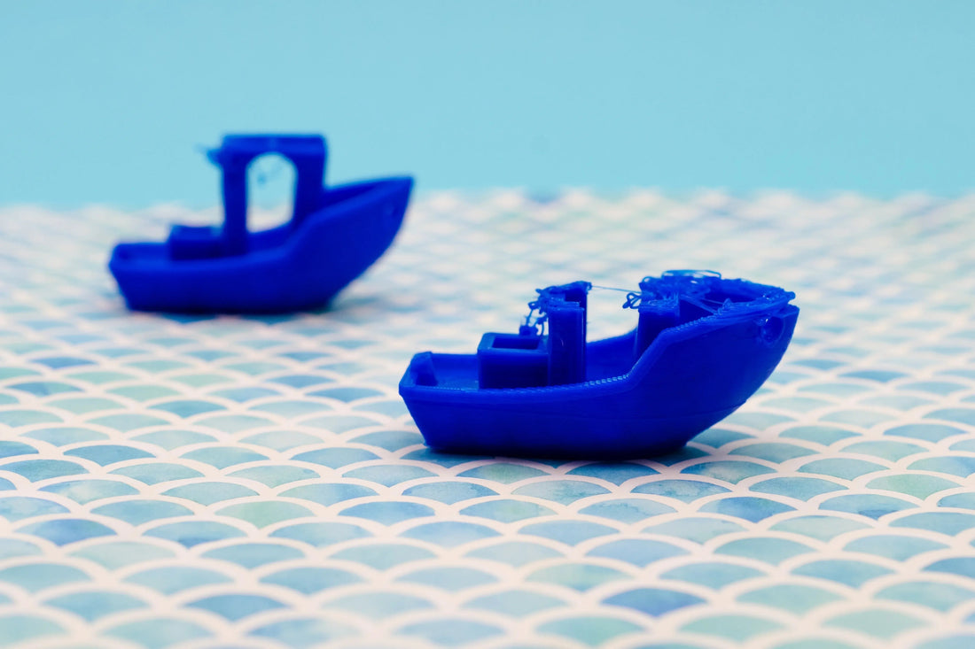 Two blue 3D printed boats on patterned surface, highlighting 3D printing issues