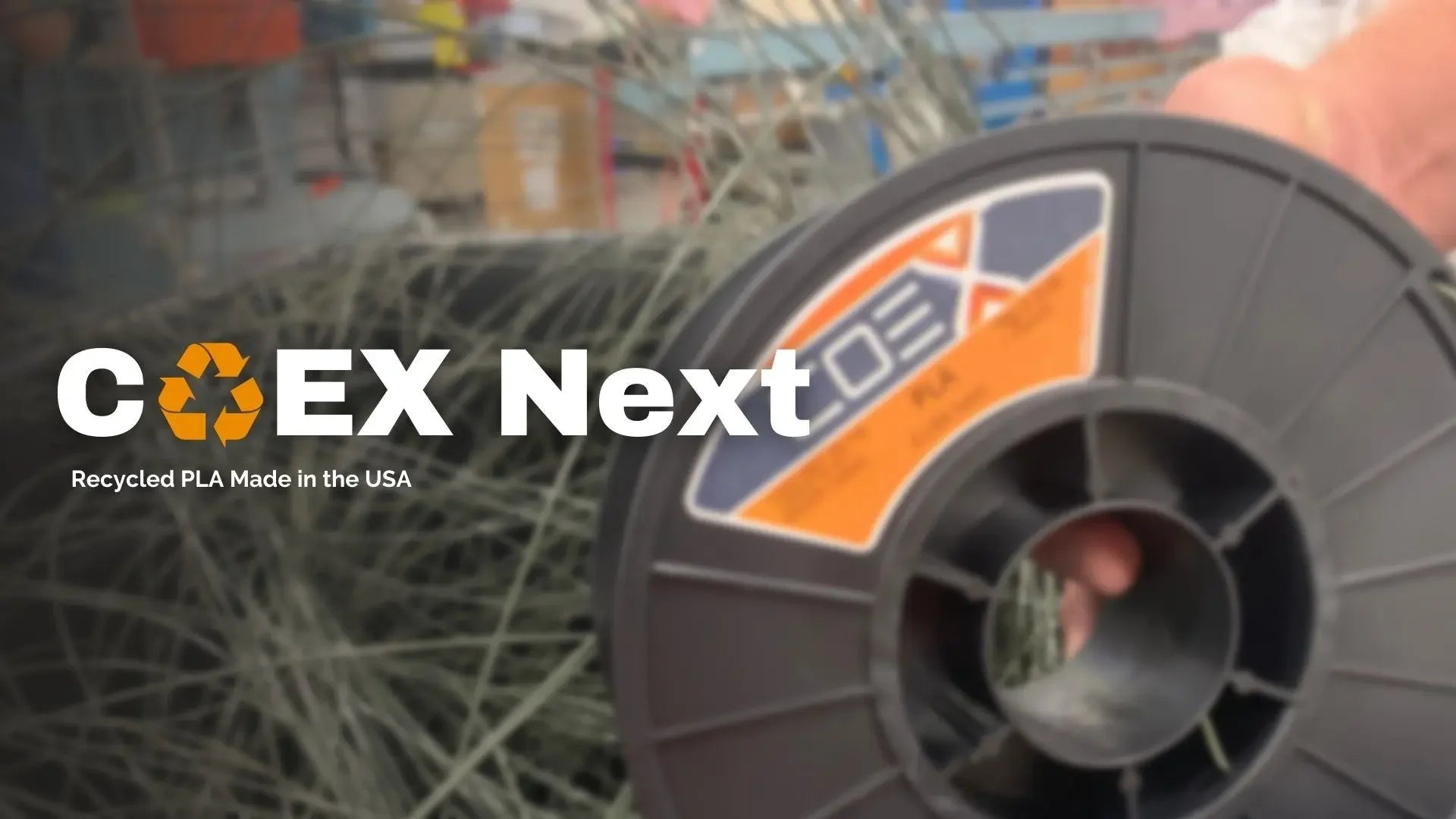 COEX Next recycled PLA 3D printer filament spool held in hand, factory background, USA made