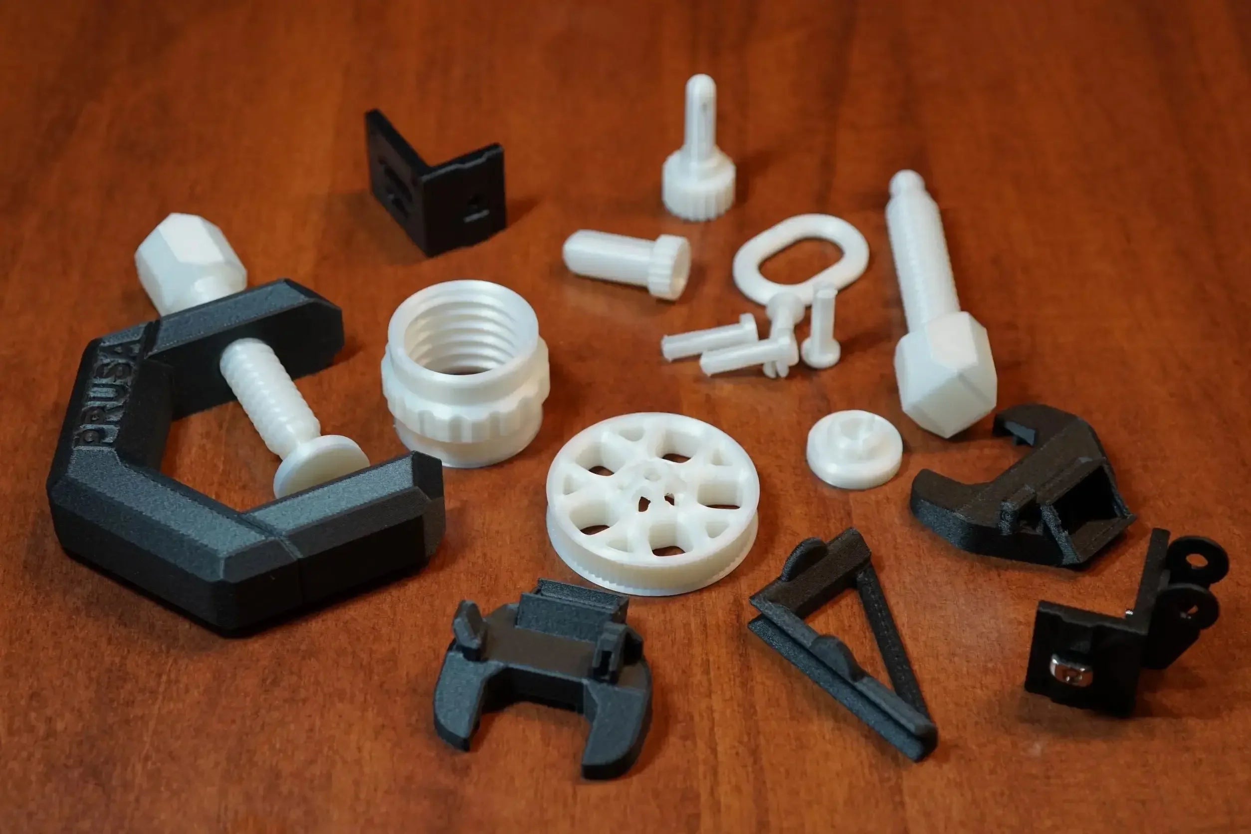 Assorted black and white 3D-printed mechanical parts on a wooden surface