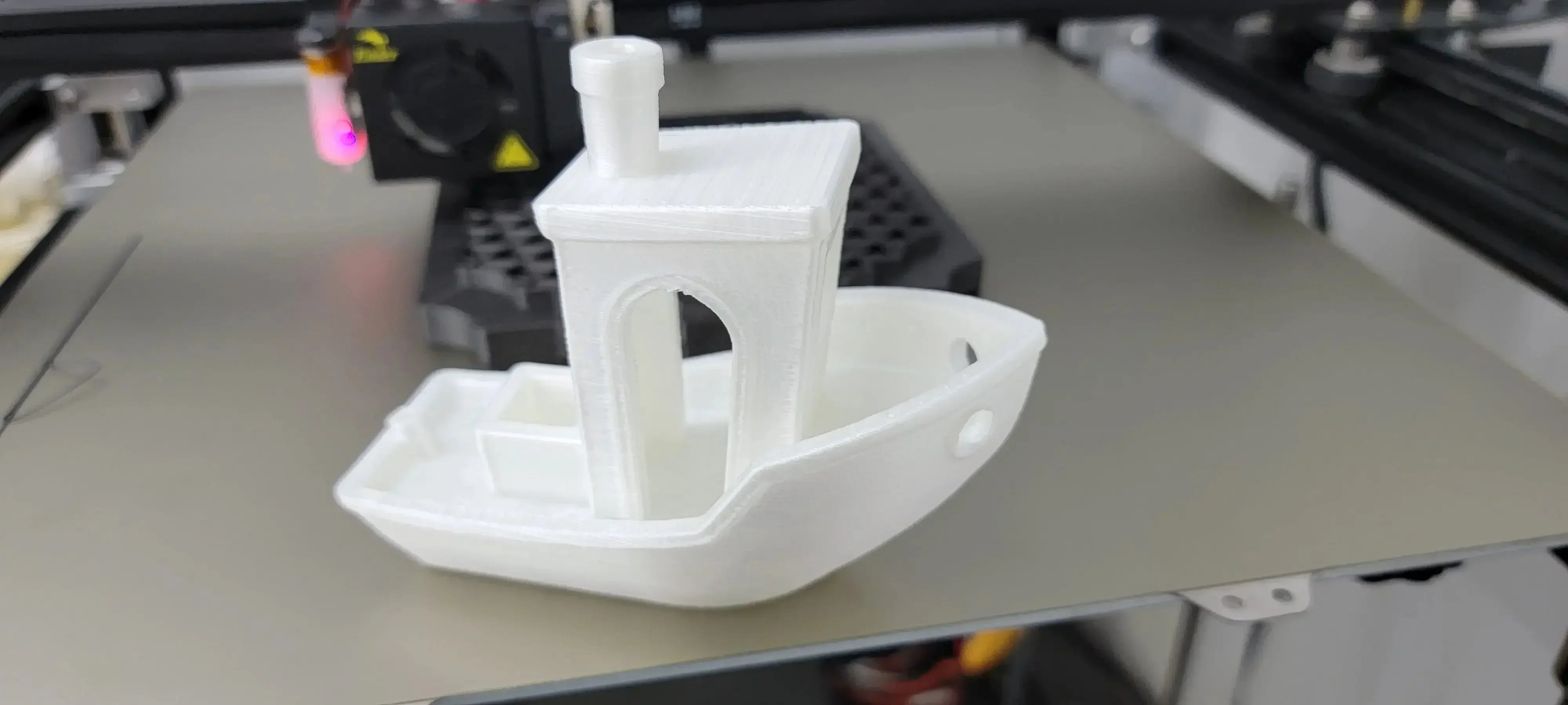 White nylon 3D printed boat model on a 3D printer bed, CoexNylex filament sample