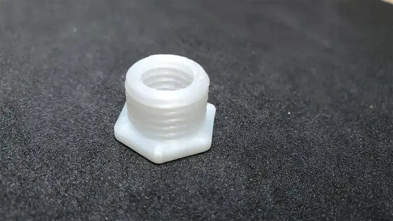 White unfilled nylon hex threaded insert on black background, 3D printed sample
